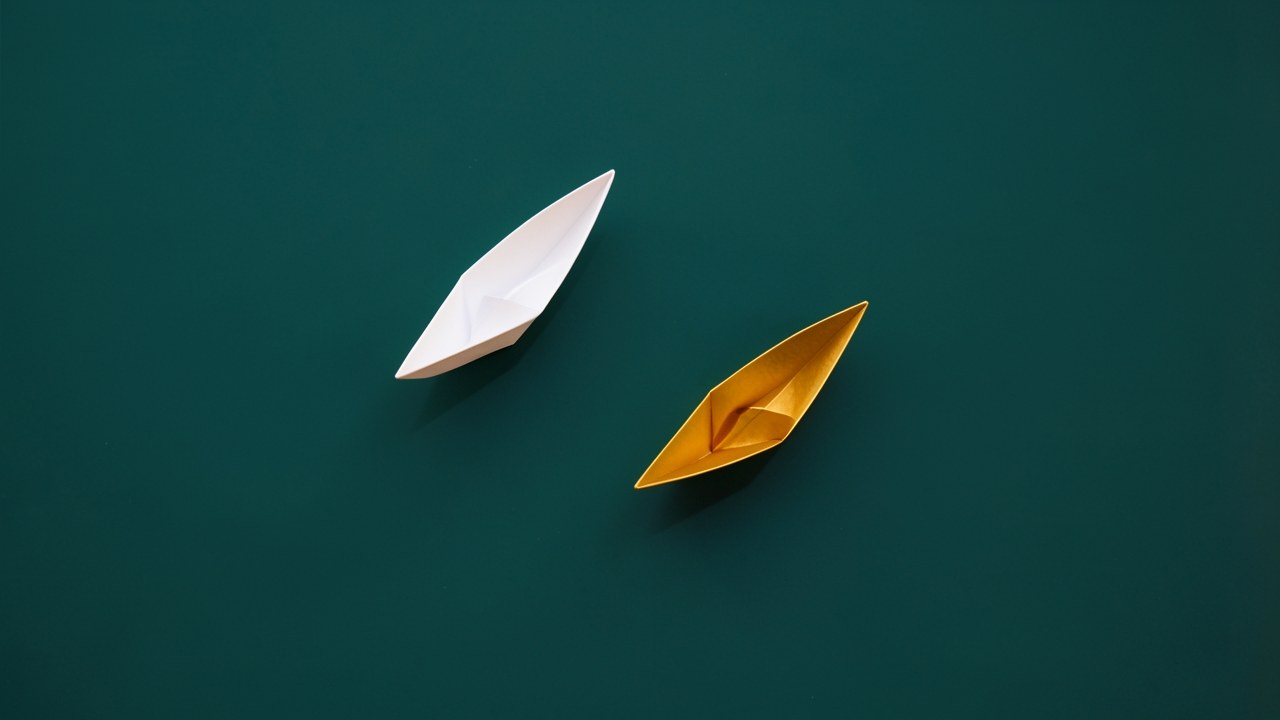 Two distinct paper boats symbolize different loan options on a calm water surface.